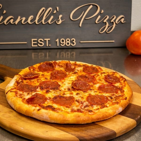 A pepperoni pizza on a wooden peel, with a "Gianelli's Pizza EST. 1983" sign in the background.