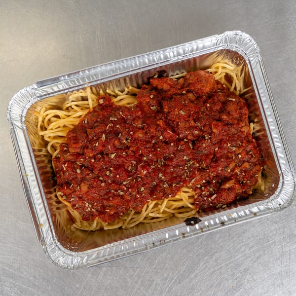 Spaghetti with rich red meat sauce and herbs in a silver foil takeout container.