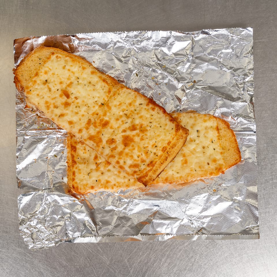 Two slices of cheesy garlic bread, golden brown and sprinkled with herbs, on crumpled aluminum foil.