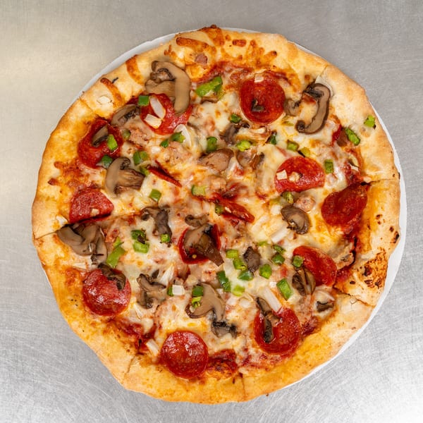 A whole pepperoni, mushroom, onion, and green pepper pizza on a white plate.