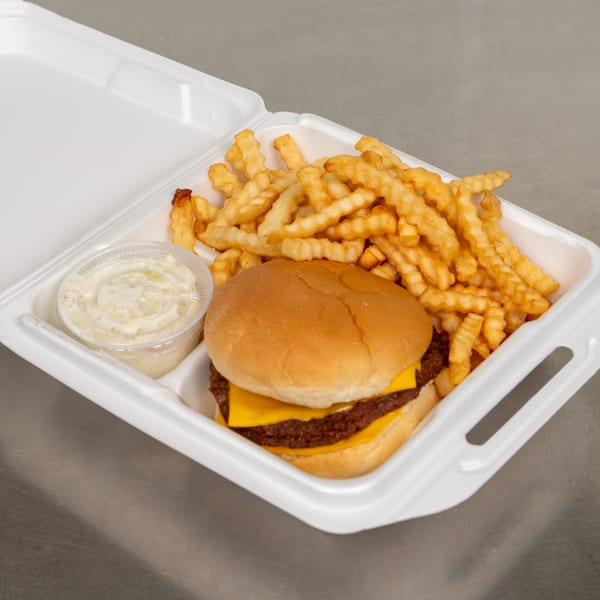 Cheeseburger with crinkle-cut fries and coleslaw in a white takeout container on a metal surface.